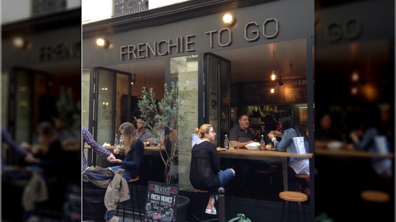 Diners eating at Frenchie To Go, gathered around windows that open inward