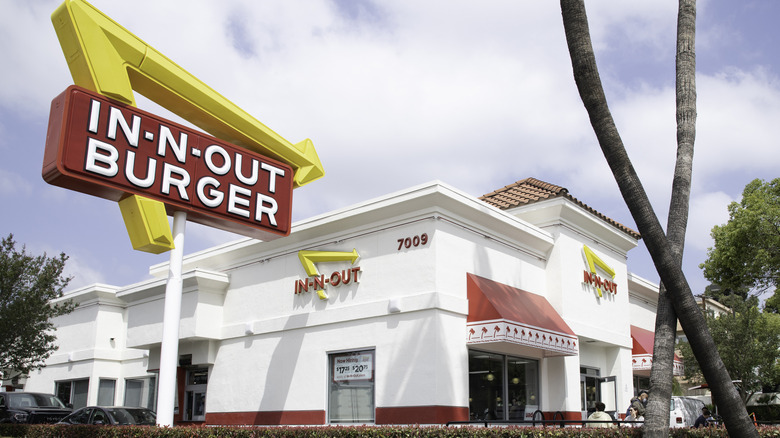 In-N-Out storefront showing sign and cars at the drive-thru window