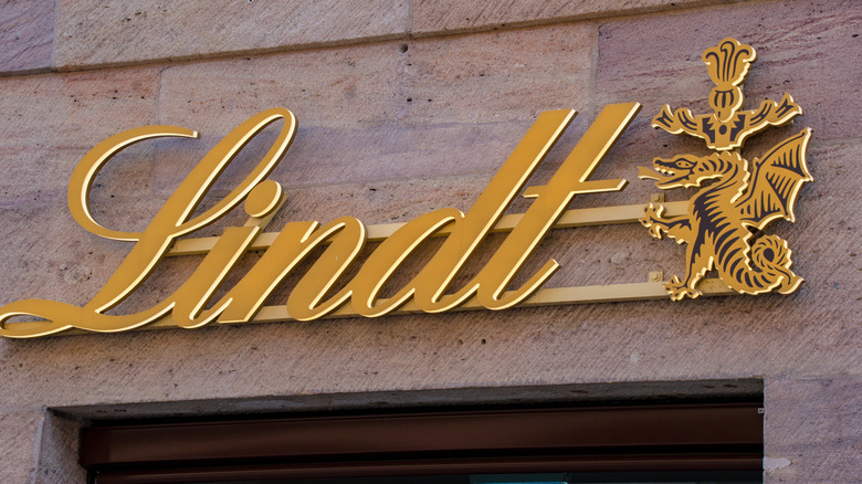 Gold Lindt sign above a doorway, next to a gryphonlike mascot