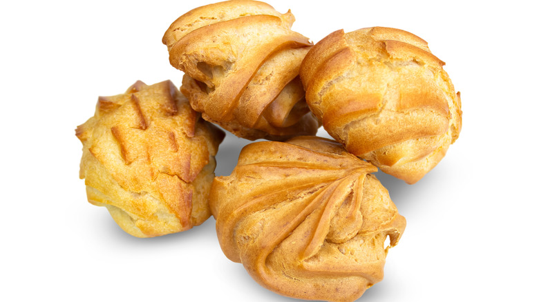 Four profiteroles up close on a white background