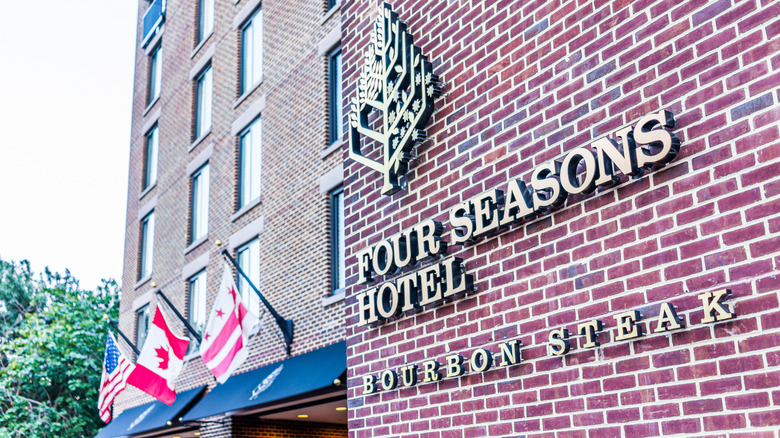 Front of Four Seasons Hotel in D.C. with a sign for Bourbon Steak on a brick wall
