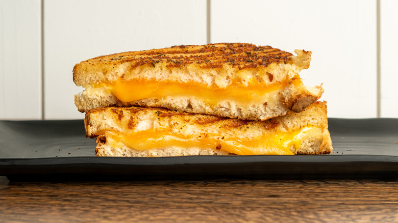 Melty grilled cheese sandwich with yellow cheese on a black plate