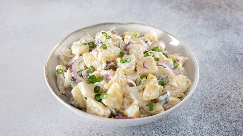 Potato salad in a bowl topped with red and green onions