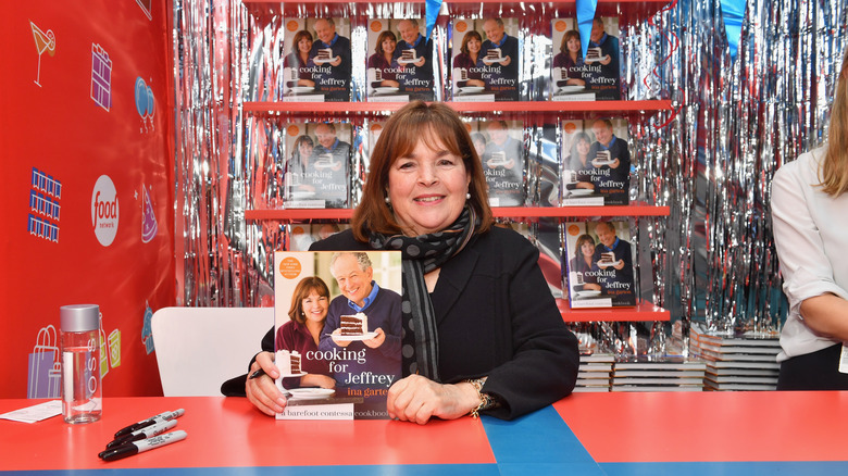 Ina Garten smiling with her "Cooking for Jeffrey" cookbook at a signing