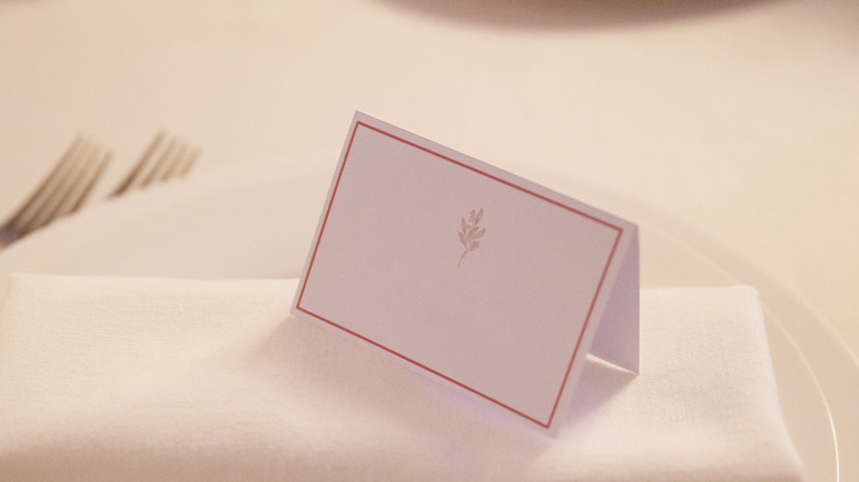 Guest name card on napkin folded on plate on table