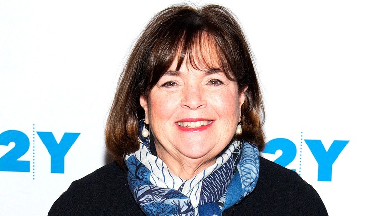 Ina Garten smiling in red lipstick while wearing a blue and white fashion scarf