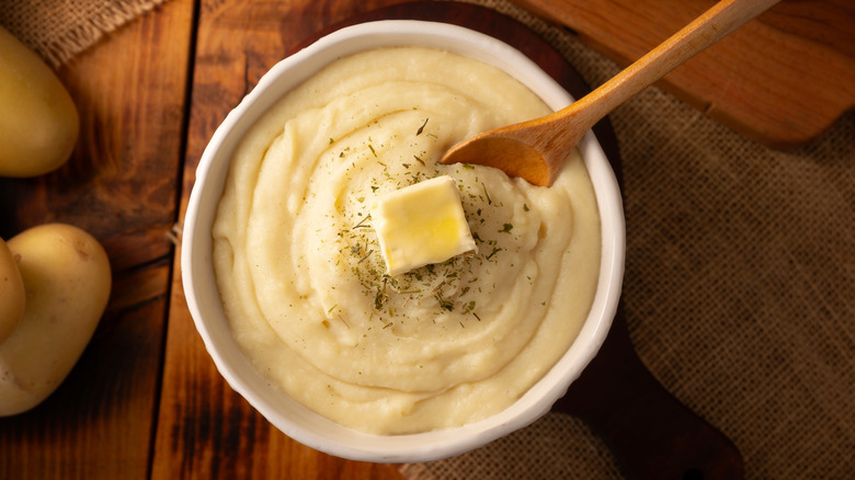 A bowl of mashed potatoes on a wooden table.