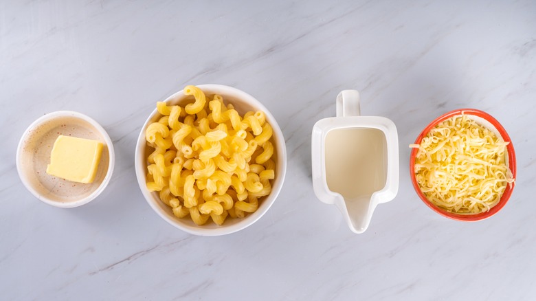 Dishes of butter, pasta, cream, and cheese to make mac and cheese.