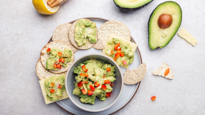 Chunky guacamole in bowl with crackers