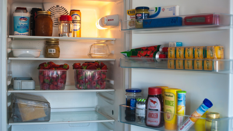 Clean and organized refrigerator with strawberries, condiments, and other food items