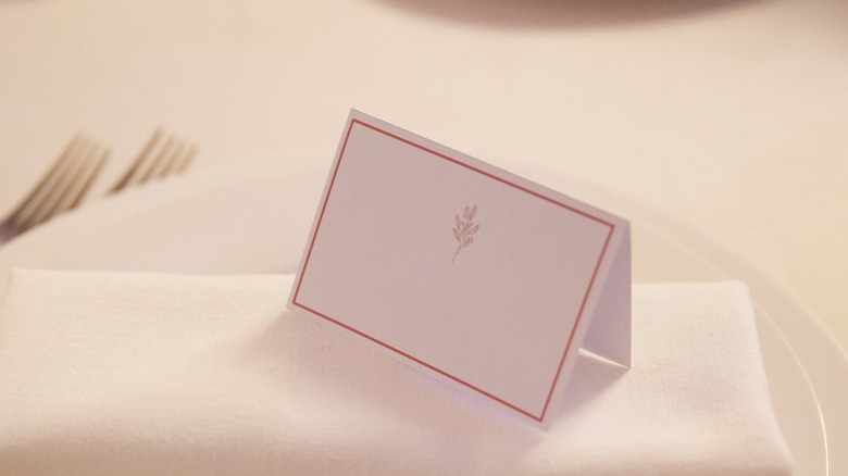 Guest name card on napkin folded on plate on table
