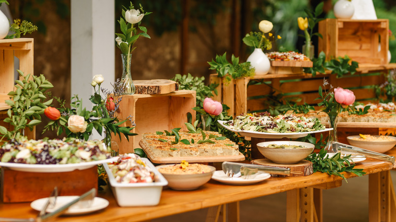 Dishes set up buffet-style on table with flower vases