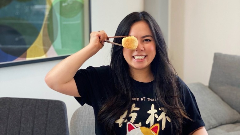 Instagram cook Tiffany Chen holding a dumpling with chopsticks in front of her eye