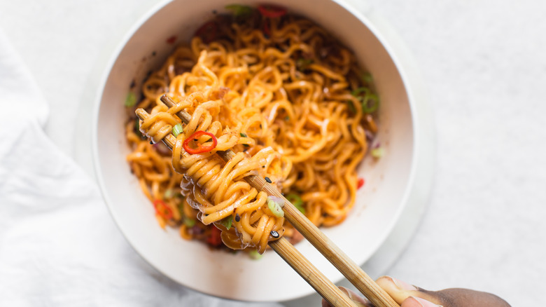 dry instant noodles in bowl, wrapped around chopsticks