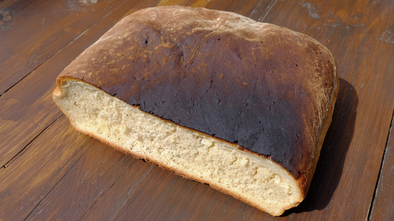 An illustrative image showing burnt loaf of bread on a wooden background