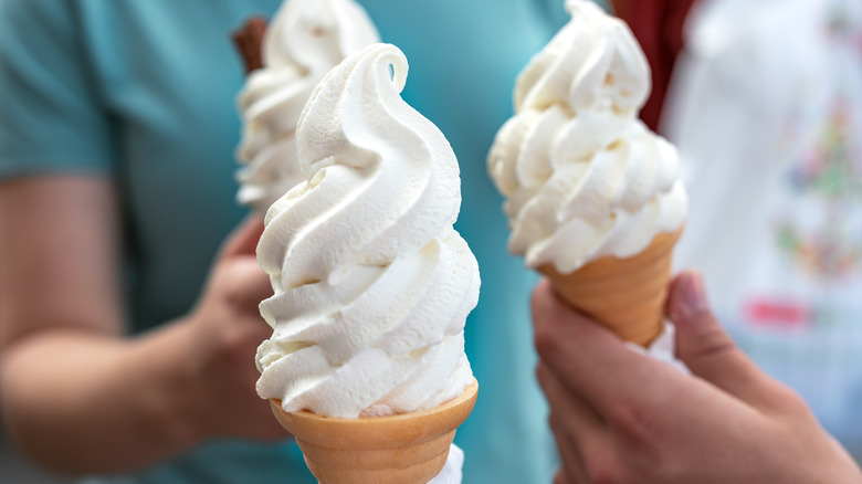 Several people holding vanilla ice cream cones
