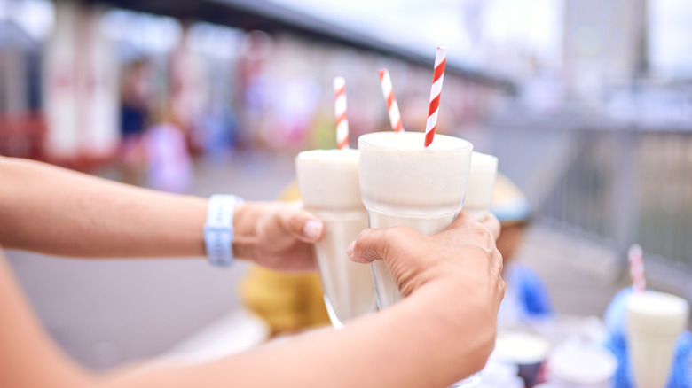 Someone carrying three milkshakes