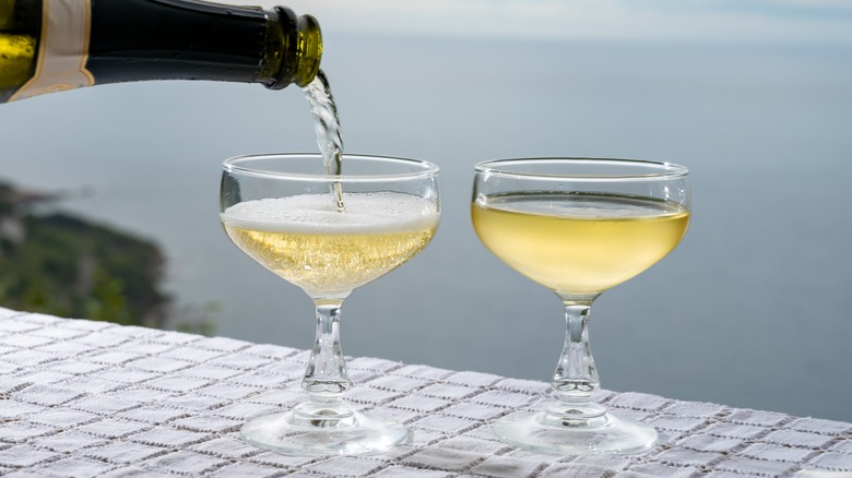 Champagne is poured into two coupe glasses
