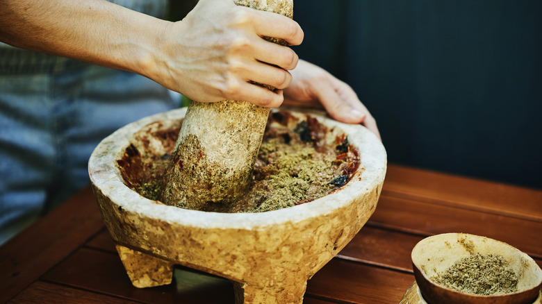 close-up of hands using molcajete