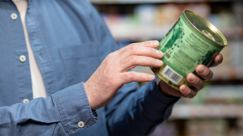 Close-up of person examining canned food label