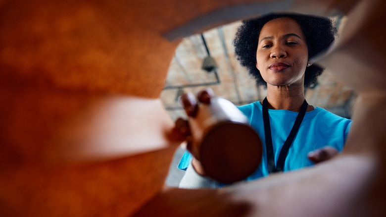 woman taking can out of paper grocery bag