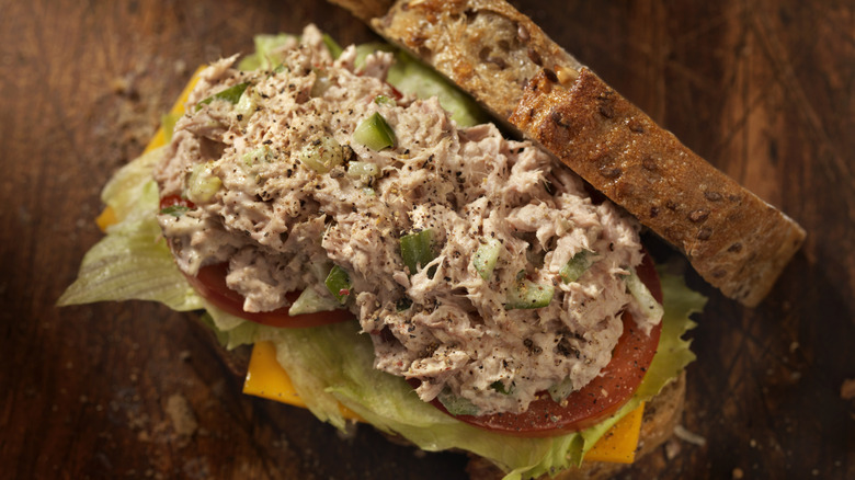 Tuna salad sandwich on seeded bread with lettuce, tomato, and cheese