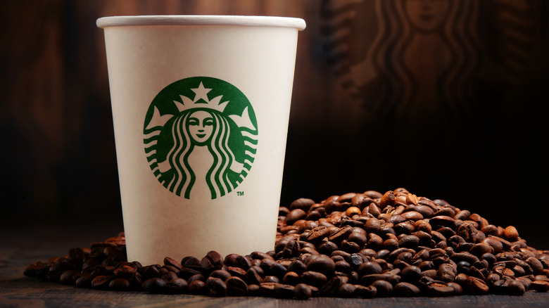 A Starbucks cup surrounded by coffee beans.