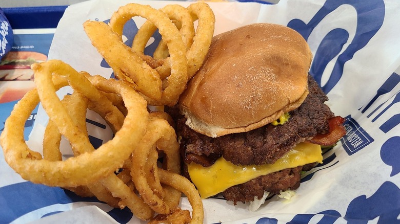 A Wisconsin butterburger with melty cheese and a side of onion rings next to it.