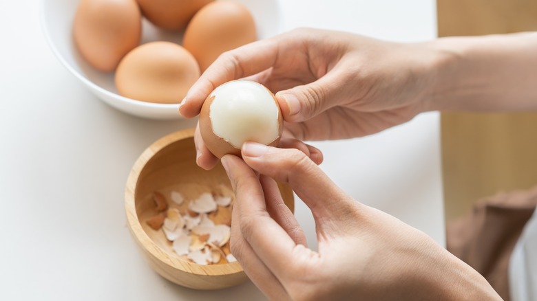 Hands peeling the shell off of a hard-boiled egg