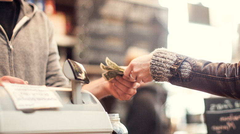 handing over cash at a cash register