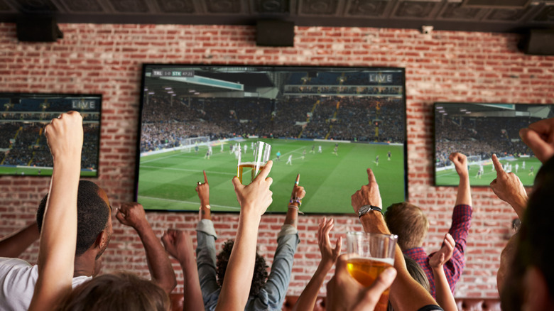 People cheering while watching soccer at a sports bar