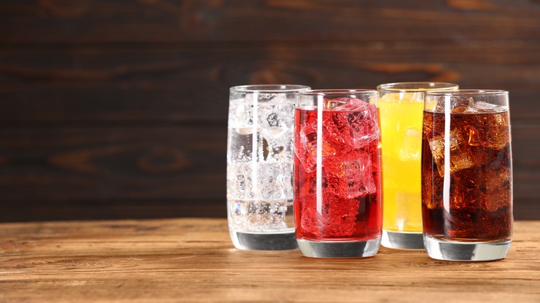 Glasses of colorful iced drinks on a wooden surface