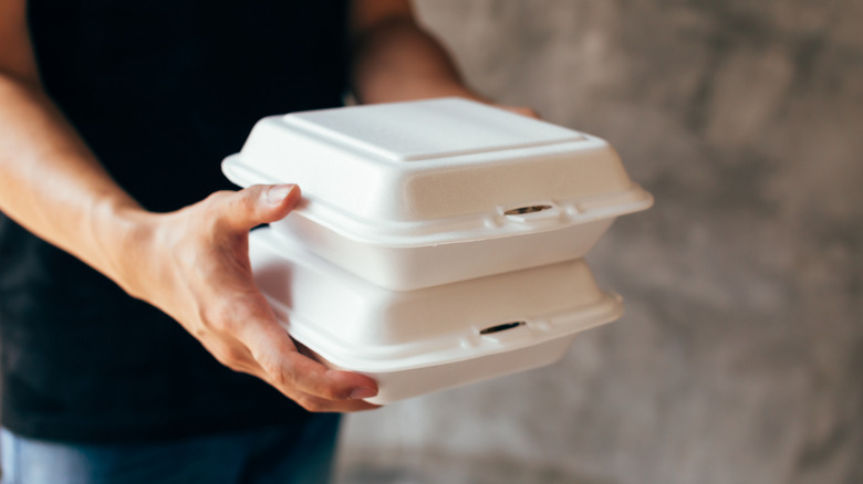 Person holding two white styrofoam containers
