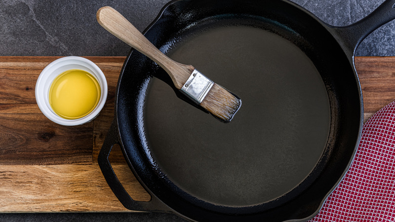 A cast iron pan being brushed with olive oil