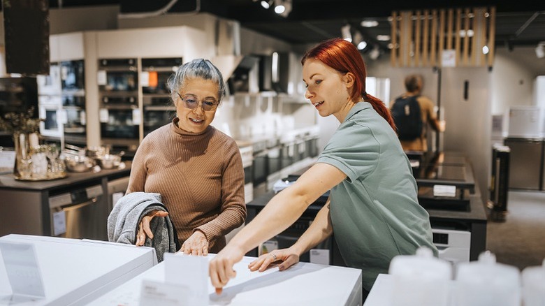 Sales associate helping customer pick out kitchen appliances.
