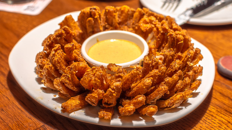 A fried Blooming Onion at Outback Steakhouse with a bowl of honey mustard in the center