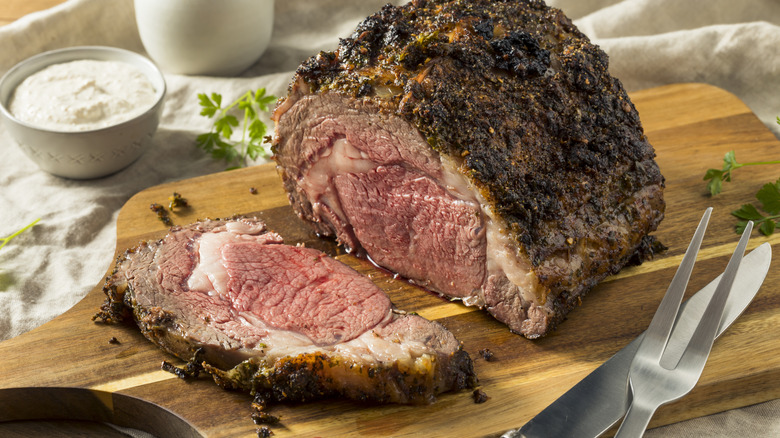 Slice prime rib roast on a wooden cutting board
