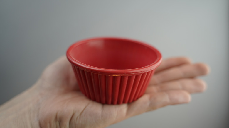 A person holding a red silicone cupcake liner.