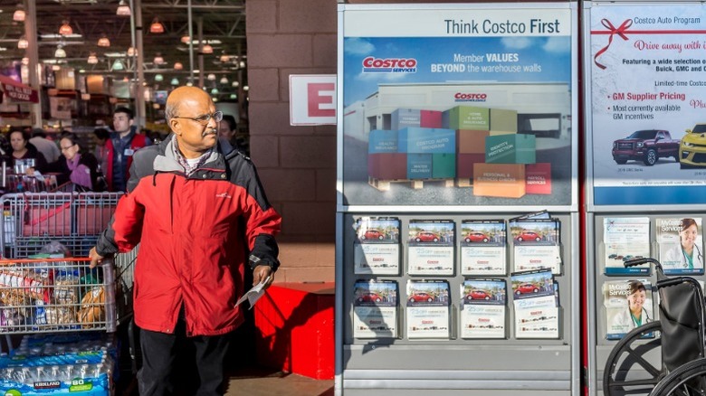 A customer with a receipt and full cart leaving a Costco.