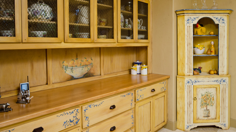 Cabinets and a cupboard both appear in a sunny kitchen.