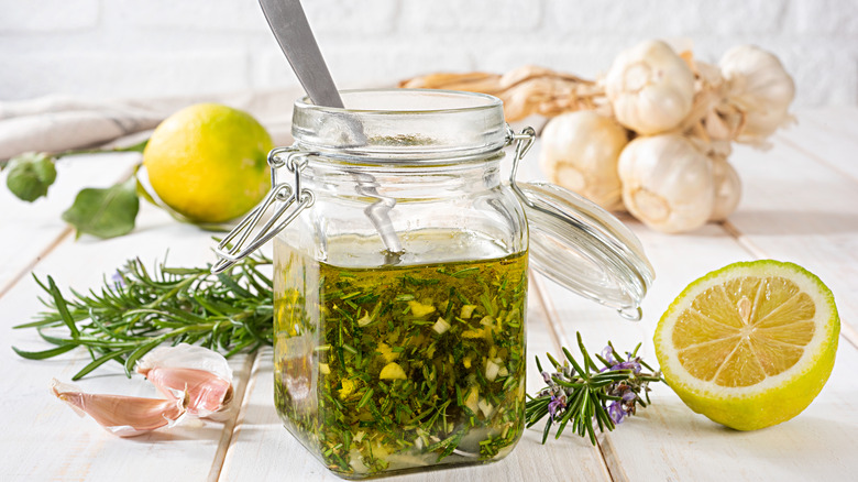 Jar of herby salad dressing surrounded by ingredients