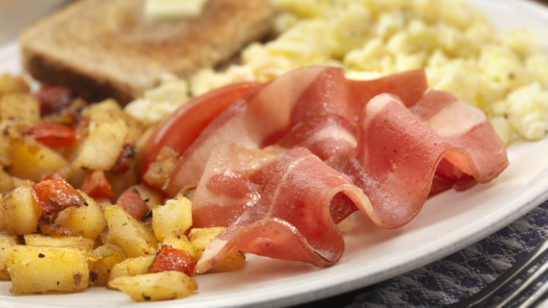 Turkey bacon on plate with potatoes, eggs, and toast