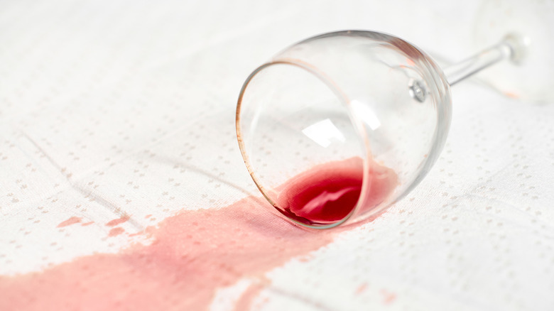 Red wine stains spread across a white fabric.