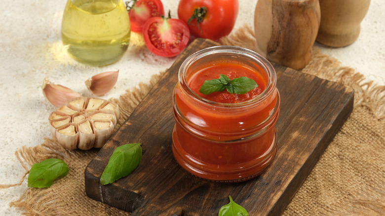 A jar of marina sauce delicately displayed on a wooden board