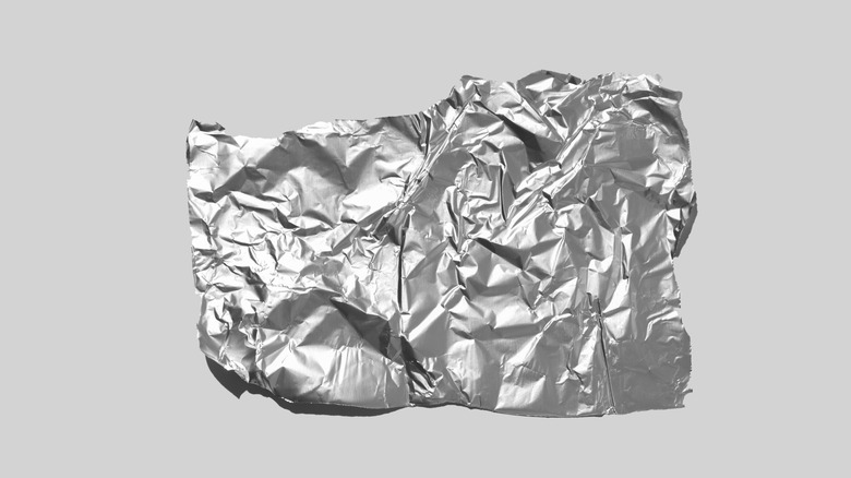 Shiny piece of aluminum foil on a gray background