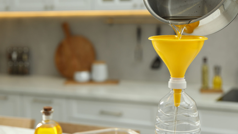 Cooking oil pouring into a yellow funnel