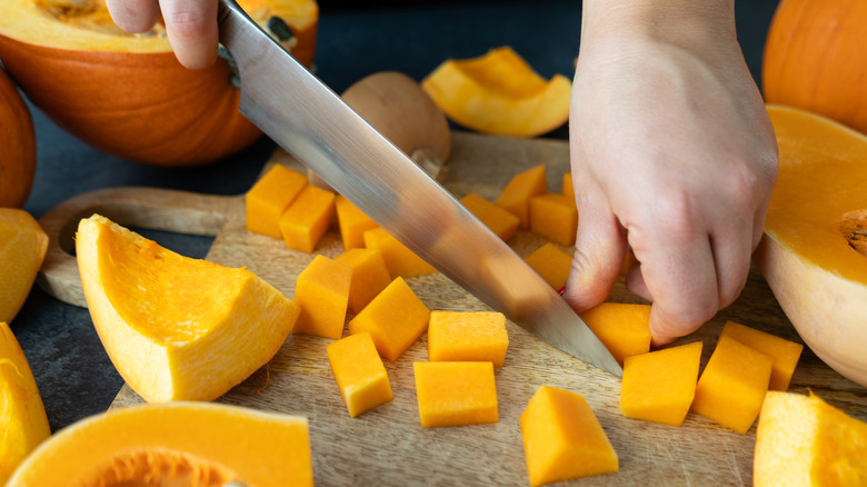 person dicing butternut squash