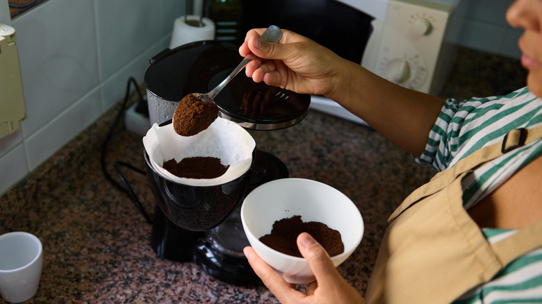 Person putting coffee grounds into a coffee maker