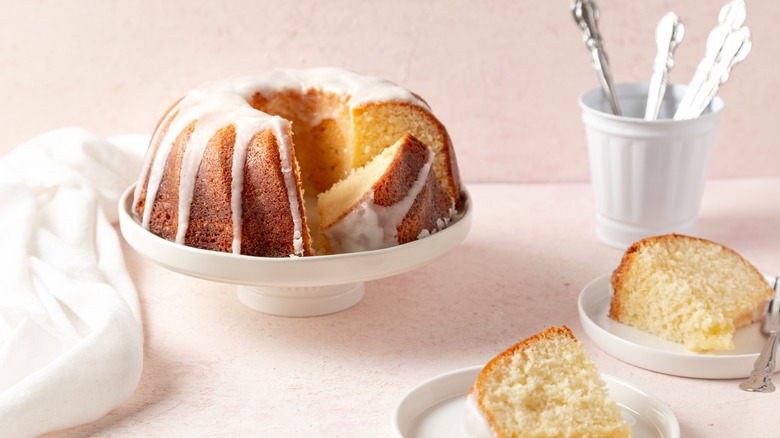 Glazed bundt pound cake on a cake stand sitting next to slices of cake on plates