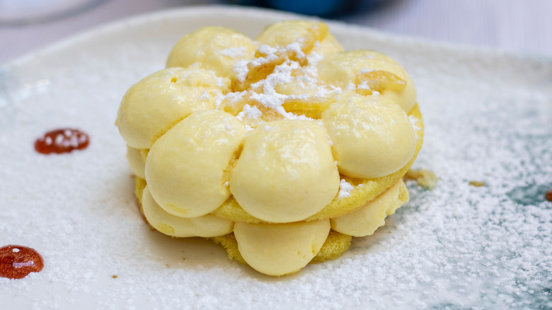 Delizia al limone or lemon delight, a sponge cake dessert featuring crema al limone garnished with powder sugar and candied lemon peel
